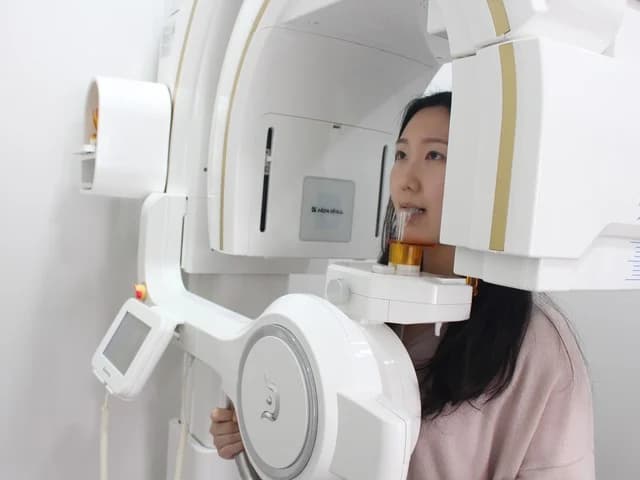 환자가 디지털 3D CT 촬영 장비 앞에 서서 촬영을 받는 모습.